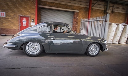 grey Porsche side view whilst being drove